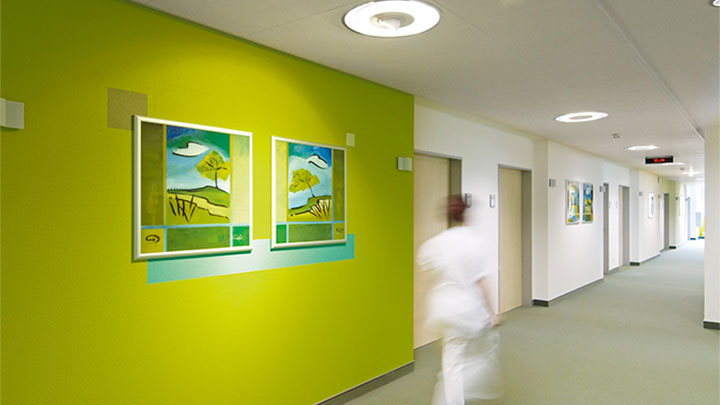 Enfermeira a caminhar num corredor iluminado pela Philips na clínica psiquiátrica