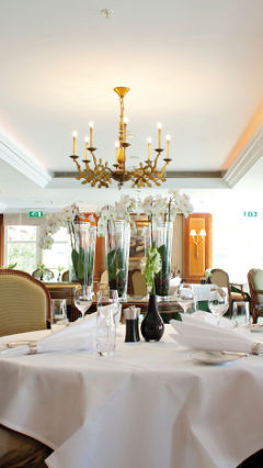 Duas pessoas estão sentadas a uma mesa do Restaurante La Rive, à luz da iluminação Philips para hotelaria