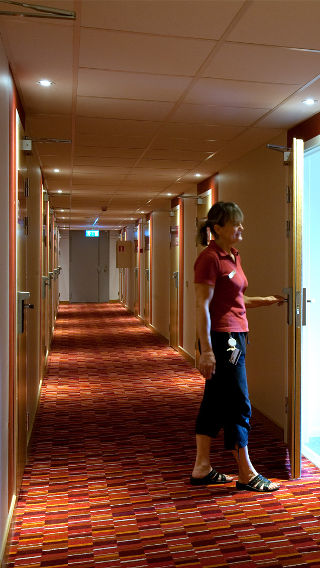 Uma mulher num corredor do Spar Hotel, iluminado pela iluminação Philips de hotéis