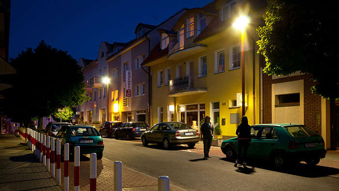 Pessoas a caminhar na rua à noite iluminadas por iluminação de rua Philips