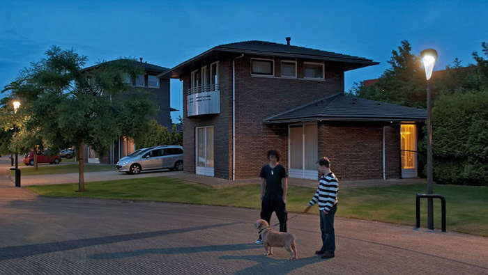 Duas pessoas a caminhar com o cão numa rua iluminada por iluminação citadina Philips