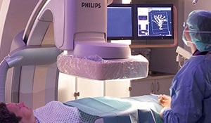 Médicos a examinar um doente numa máquina de raios X
