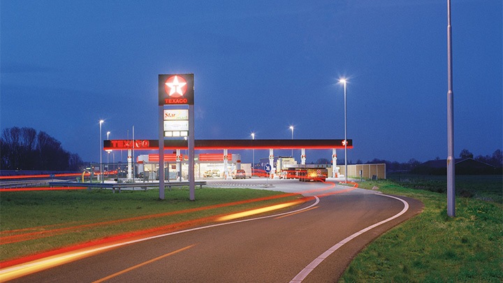 Um posto de combustível da Texaco na saída da autoestrada, iluminado de forma atraente ao anoitecer – iluminação exterior cativante
