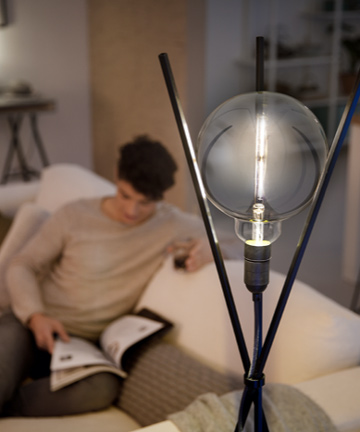Homem a ler junto a uma lâmpada LED de design moderno da Philips 