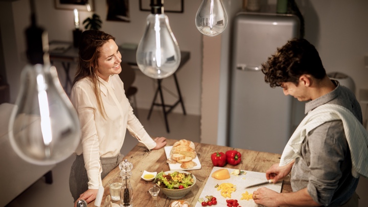 Vista de cima de um homem e uma mulher a preparar o jantar numa cozinha bem iluminada