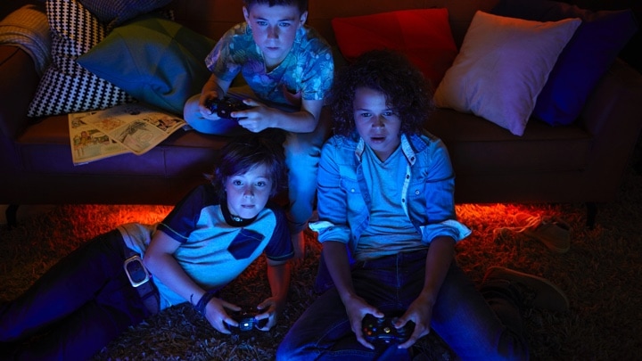 3 rapazes a jogar videojogos com iluminação ambiente