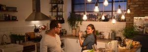 "Cozinha moderna com luzes pendentes LED de estilo vintage que iluminam duas mulheres a jantar, criando um ambiente acolhedor e convidativo."