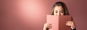 "Rapariga a espreitar por cima de um livro cor-de-rosa contra um fundo suave iluminado por LED, apresentando uma iluminação quente e uniforme para ambientes de leitura confortáveis."