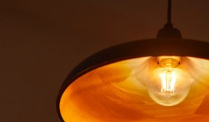 "Lâmpada de filamento LED de estilo vintage em candeeiro pendente, emitindo um brilho dourado quente, apresentando uma iluminação nostálgica eficiente em termos energéticos para um ambiente doméstico acolhedor."