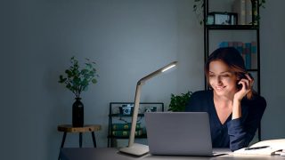 "Criança a estudar à secretária com candeeiro de trabalho LED ajustável, proporcionando uma iluminação ideal para os trabalhos de casa num espaço de aprendizagem em casa colorido."
