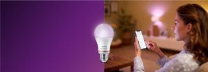 "A mulher controla a iluminação LED inteligente através da aplicação para smartphone, criando um ambiente acolhedor na sala de estar confortável com tecnologia de casa conectada."
