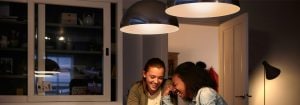 "As modernas luzes pendentes LED criam um ambiente acolhedor para duas mulheres que conversam, apresentando soluções de iluminação para a casa energeticamente eficientes."