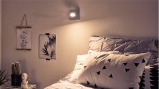 Quarto elegante com projetor LED regulável que cria um ambiente acolhedor, iluminando a roupa de cama geométrica e a decoração minimalista.